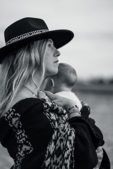 The Motherhood story - Nähe und Verbundenheit Mutter hält ihr Kind auf dem Arm und blickt in die Ferne – natürliche Mutterschaftsfotografie.
