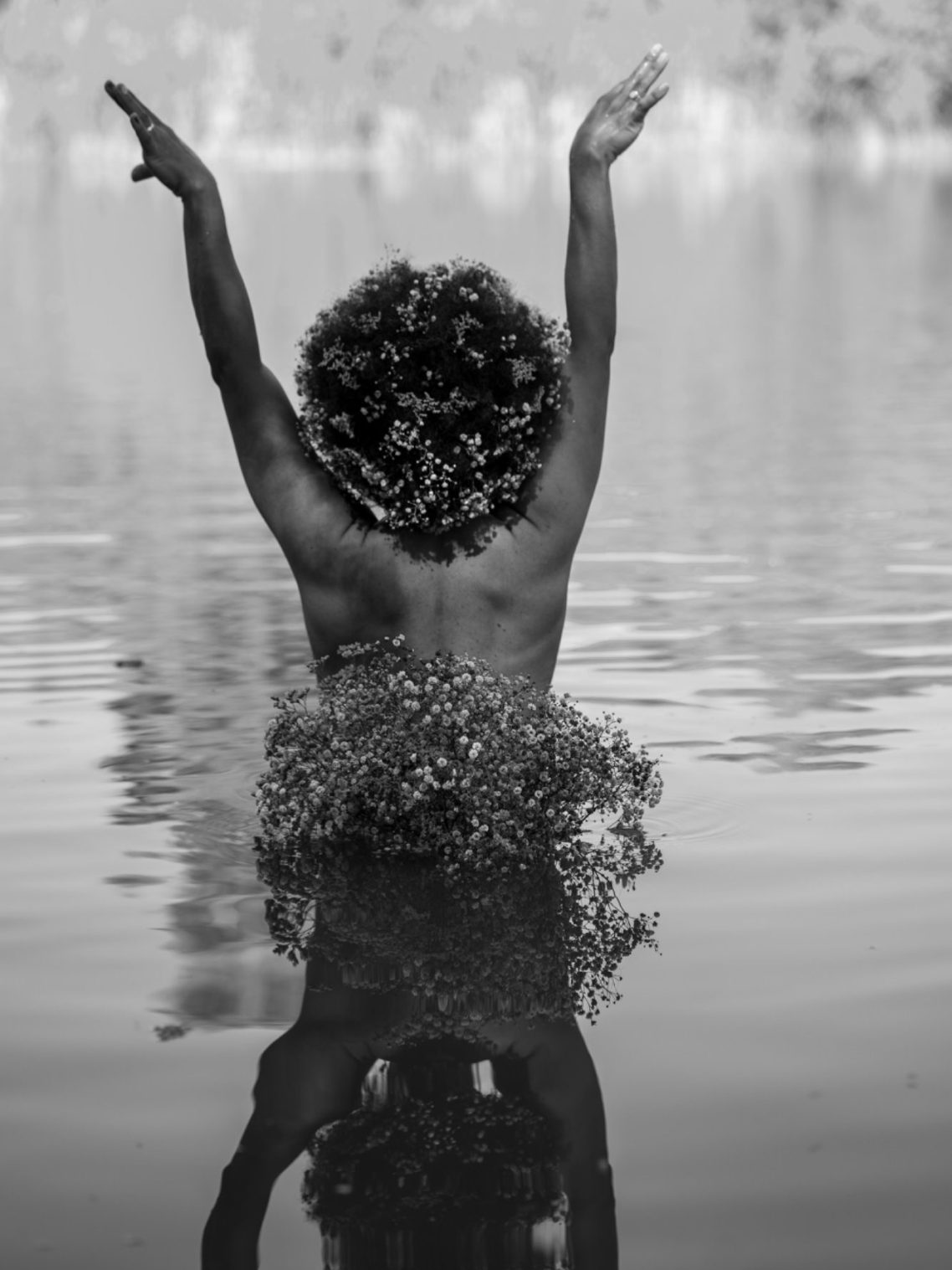 Erblüht – Selbstliebe in Bildern Authentische Frauenfotografie – eine Frau mit Afro Haar steht im Wasser und öffnet sich dem Licht.