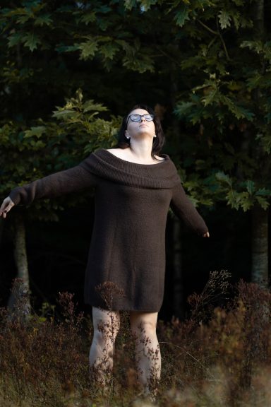 Sich zeigen dürfen | Empowerment Fotoshooting in der Natur Frau steht mit ausgebreiteten Armen im Abendlicht im Grünen, Moment von Selbstannahme beim Empowerment Fotoshooting